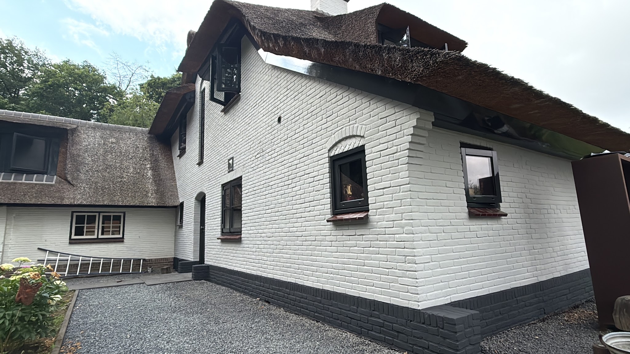 Wit geschilderde woning met rieten dak en donkere kozijnen
