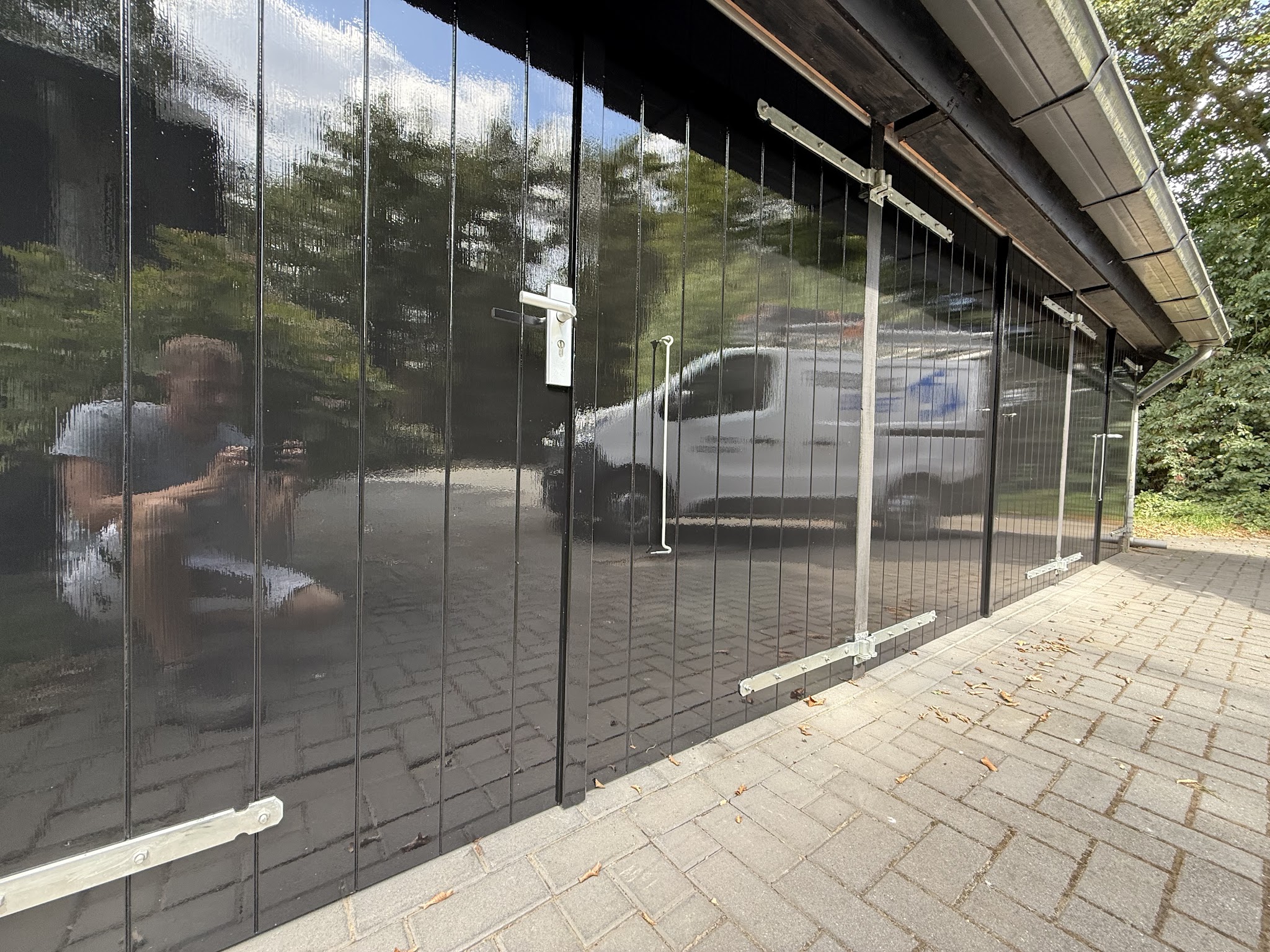 Zwarte hoogglans geschilderde gevelpanelen waarin de bus van Schildersbedrijf ter Harmsel weerspiegelt